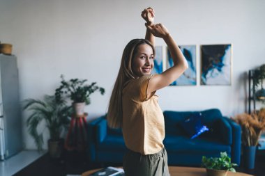 Avrupalı bir kız gülümsüyor ve evde kameraya bakıyor. Ev hayatı kavramı. Modern kadın fikri işte. Gündelik kıyafetler giyen genç bir bayan. Stüdyo dairenin içi.