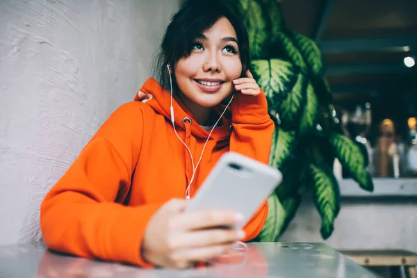 Szczęśliwa Azjatka Zębatym Uśmiechem Odwraca Wzrok Siedząc Stołówce Korzystając Smartfona — Zdjęcie stockowe