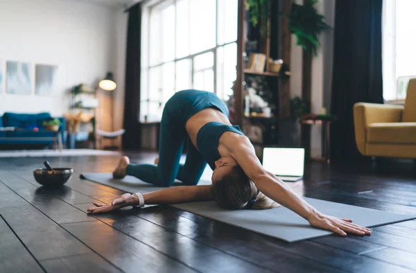 欧洲女孩在家里的健身垫上练习瑜伽 健康生活方式的概念 穿着运动服和赤脚的年轻迷人的女运动员 工作室公寓的内部 — 图库照片