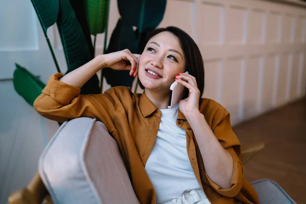 Tankeväckande Asiatisk Kvinna Pratar Mobiltelefon Medan Sitter Och Vilar Fåtöljen — Stockfoto