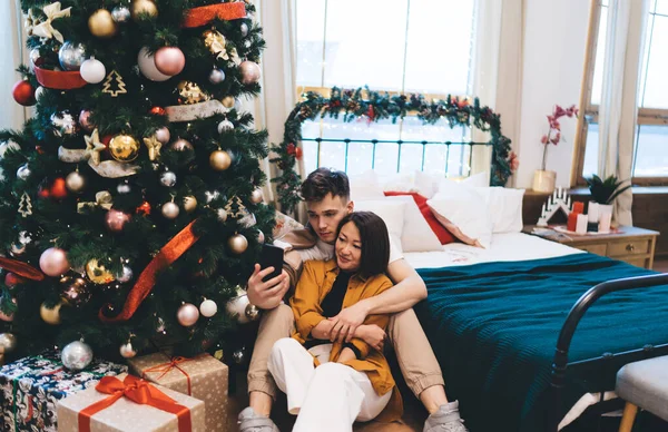 Casal Multirracial Levando Selfie Smartphone Entre Cama Árvore Natal Casa — Fotografia de Stock