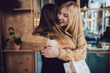 Uzun saçlı, gözleri kapalı, sıcak örgü süveter giyen mutlu bayan tatilleri birlikte kutlarken en iyi arkadaşını rahat kafeye götürüyor.