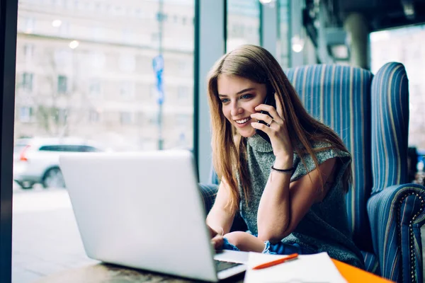 Femeia Tânără Veselă Îmbrăcăminte Casual Vorbind Telefon Folosind Laptop Pentru — Fotografie, imagine de stoc