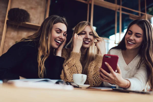 3名身着休闲装的年轻女子在咖啡店里一边看电视一边笑 — 图库照片