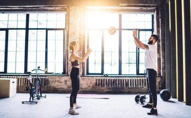 Spor giyim kuşağındaki atletik erkek ve kadının gündüz spor salonunda antrenman yaparken birbirlerine top atmaları.