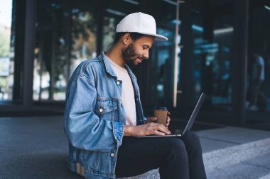 Şehir merdivenlerinde uzak mesafeli iş yapan yetenekli bir erkek bilişim uzmanı serbest yaşam tarzını koruyan, modern dizüstü bilgisayardan 4G 'ye bağlanan yayın haberleri okuyan yenilikçi bir adam.