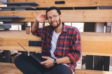 Uzaktan kumandalı, yetenekli erkek nesil Z ile uzaktan kumandalı kameraya bakarak modern dizüstü bilgisayar teknolojisi kullanan netbook kullanan Latin bilişim uzmanının portresi.