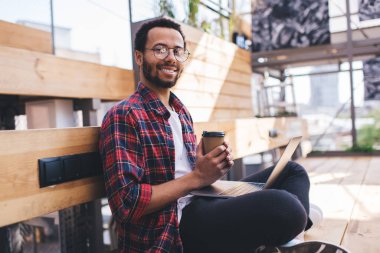 Başarılı bilişim geliştiricisinin portresi bilgisayardaki kablosuz bağlantıyı kullanarak serbest işten keyif alıyor, klasik gözlüklü başarılı hipster adam çevrimiçi öğrenirken kameraya gülümsüyor.