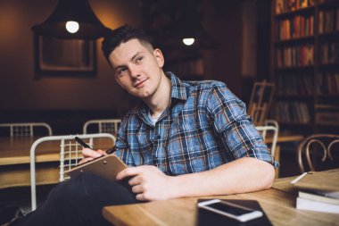 Sınav hazırlıkları sırasında eğitim fikrini düşünürken başka yöne bakan düşünceli bir erkek öğrenci. Masa başında bilgi edinme üzerine kafa yoran 20 yaşında beyaz bir adam.