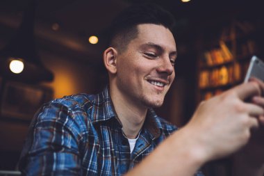 Gülümseyen erkek blogcu modern cep telefonu aygıtını kullanarak kablosuz tarama uygulaması ile kablosuz internete bağlanıyor, neşeli nesil Z modern akıllı telefon teknolojisiyle ilgili SMS mesajı alıyor