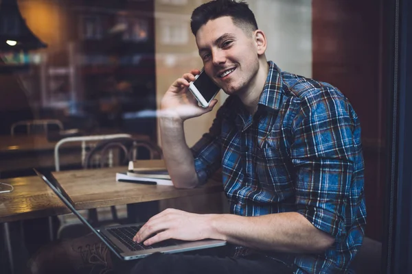 Akıllı rahat gömlekli neşeli erkek metin yazarının portresi. Uzaktan iş yapmak için dizüstü, danışmanlık yapmak için akıllı telefon kullanıyor. Mutlu adam iletişim hizmetleri ile iletişim kuruyor.
