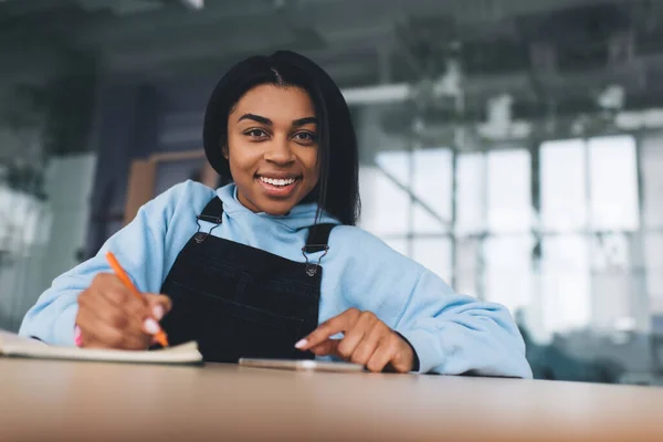 Menina Negra Escrevendo Algo Notebook Com Caneta Usando Telefone Celular — Fotografia de Stock