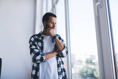 Günlük kıyafetler giymiş hippi bir adam şirket ofisinde çalışırken pencereden içeri bakıyor, şık gömlekli dalgın hippi öğrenci bilgi ve fikirleri düşünüyor.