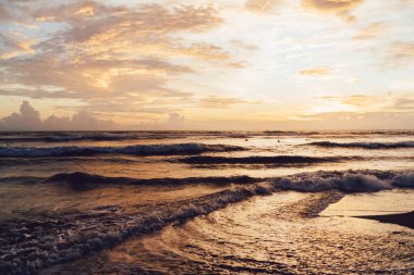 Sıcak tropikal bir ülkenin sahillerinde, fırtınalı ve uçsuz bucaksız okyanusun üzerinde yüzen büyük bulutlarla görkemli, parlak bir günbatımı.