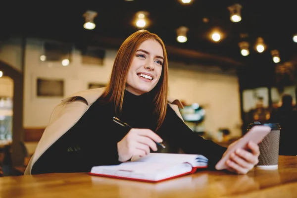 Positive Junge Frau Trendiger Kleidung Sitzt Holztisch Mit Notizbuch Während — Stockfoto