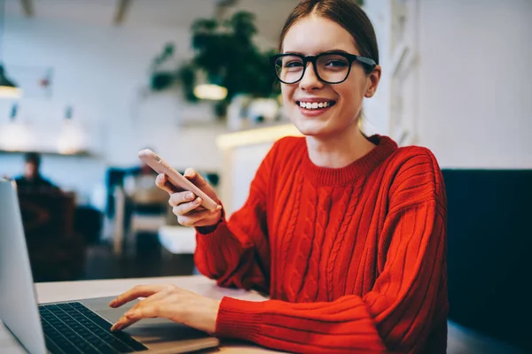 Lachende Vrouwelijke Freelancer Rode Trui Bril Kijken Naar Camera Tijdens — Stockfoto