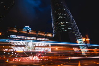 Aydınlatılmış modern gökdelenden, geceleri Hong Kong 'un büyük bir şehrinde yol kenarında parlayan ışıklar.
