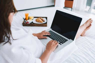 Kuala Lumpur 'da internette bilgi ararken bornozlu ve dizüstü bilgisayarında yazan tanınmayan bir kadının üstünden.