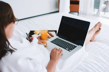 Yukarıdan gelen gözlüklü, gözlüklü, internette gezinen ve Kuala Lumpur 'da portakal suyu içen isimsiz bir kadın.