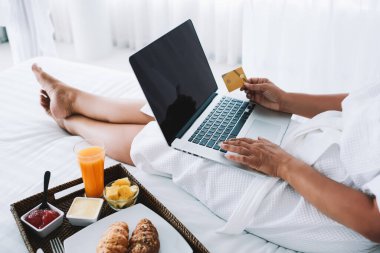 Beyaz bornozlu, tanınmayan bir kadın. Kuala Lumpur 'da alışverişe giderken dizüstü bilgisayar başında yatıyor.