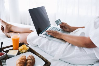 Kuala Lumpur 'daki çevrimiçi dükkanda dizüstü bilgisayarında yazan, üzerinde kredi kartı olan yüzü olmayan yüzü olmayan bir kadın.