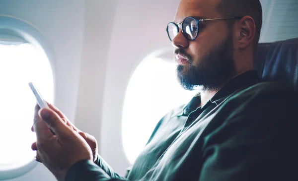 Hombre Adulto Serio Sentado Silla Avión Cerca Ventana Mientras Usa — Foto de Stock