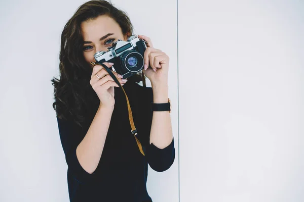 年轻的女摄影师身穿黑色毛衣和腕表 头戴复古摄影相机 站在白色背景下 — 图库照片