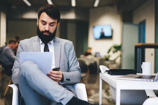 Nachdenklicher Büroangestellter Mit Bart Formeller Kleidung Sitzt Mit Überkreuzten Beinen — Stockfoto