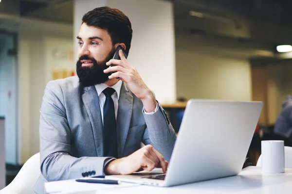 사무실에서 전화로 통화하는 양복을 테이블에 노트북을 탐색하는 포괄적 기업인 — 스톡 사진