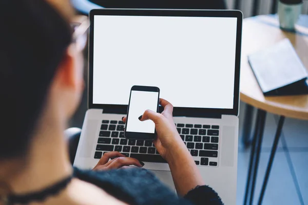 Rückansicht Frau Tippt Auf Laptop Und Liest Nachricht Auf Smartphone — Stockfoto