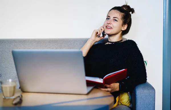 Mladá Studentka Ležérní Oblečení Mluví Smartphone Sedí Útulné Pohovce Učebnicí — Stock fotografie