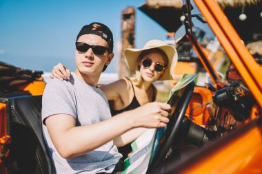 Düşünceli bir kadının elinde harita olan bir adamın omzunu kaldırırken arabada oturup güzergahı seçmesinin yan görüntüsü.