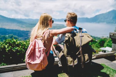 Genç bayan ve erkek turistlerin günlük kıyafetleri ve güneş gözlükleriyle üstte oturarak manzaranın keyfini çıkardıkları arka plan.