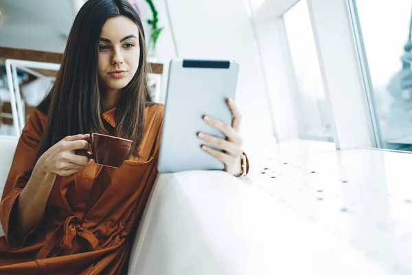 Pensive Young Long Haired Ethnic Female Browsing Tablet Drinking Hot — Stock Photo, Image