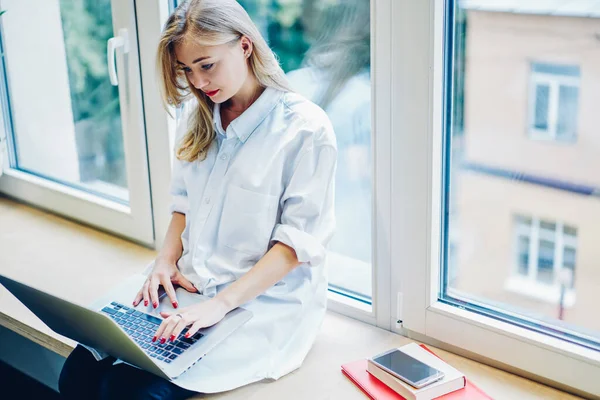 Focused Young Woman White Clothes Sitting Windowsill Laptop Knees Looking — 图库照片