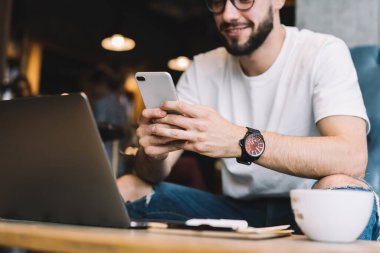 Taşınabilirlik bildirimini kontrol etmek için cep telefonu teknolojisi kullanan erkek programcının kesilmiş görüntüsü, çevrimiçi sohbet ve mesajlaşma için cep telefonu aygıtı kullanan elektronik akıllı blogcu