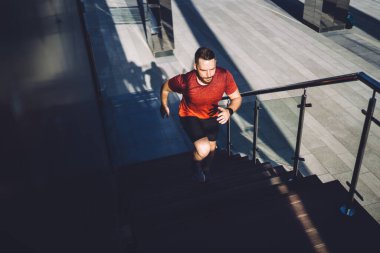 Sağlıklı bir yaşam sürüp yaz günlerinde ısınırken üst kata koşan kendinden emin bir erkek koşucu.