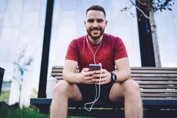Handsome Smiling Sportsman Activewear Sitting Wooden Bench Holding Mobile Phone — Stock Photo, Image
