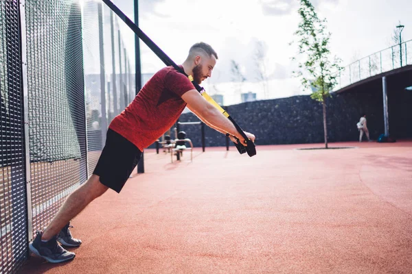 Spor ayakkabısı giymiş güçlü bir adamın spor sahasında antrenman yapması ve diğer tarafa bakarken kollarını sallaması.