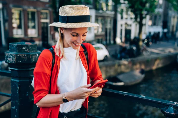 Neşeli bayan gezgin, Amsterdam 'da yolculuk yaparken köprünün korkuluklarına yaslanırken cep telefonunu karıştırıyor.