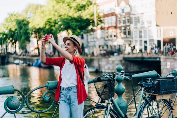 위에서 자전거를 있거나 암스테르담에서 여행하는 핸드폰으로 사진을 모자를 착용하고 여성의 — 스톡 사진