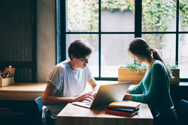 全神贯注的年轻男女学生穿着休闲装坐在舒适的咖啡店里 一起在笔记本电脑上准备考试 — 图库照片