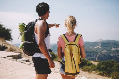Güneşli yaz günlerinde sırt çantalarıyla manzara manzarasına hayran olan tanınmamış çok ırklı turistlerin arka planı.