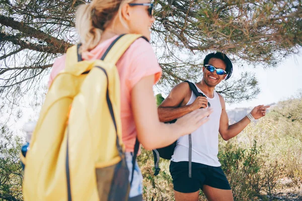 若い多人種のカップルは バックパックで旅行しながら 晴れた夏の日に田舎の歩道を一緒に歩き カジュアルな服装とサングラスを着用してください — ストック写真
