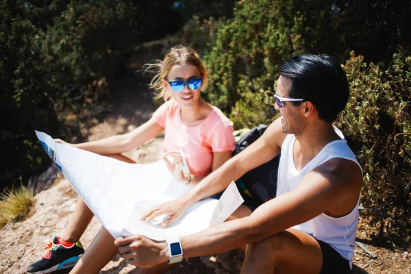 在阳光明媚的夏日 年轻的男女游客一边在山上休息一边学习地图 同时彼此凝视 — 图库照片