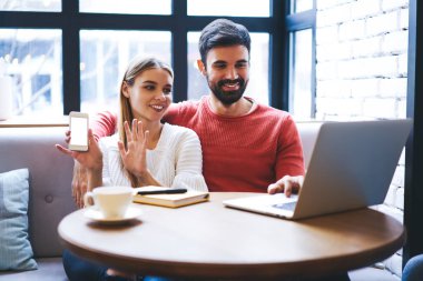 Günümüz akıllı telefonlu, gündelik kıyafetleriyle gülümseyen genç bir kadın kafeteryada otururken dizüstü bilgisayarlı erkek arkadaşının videosunu izlemeyi reddediyor.