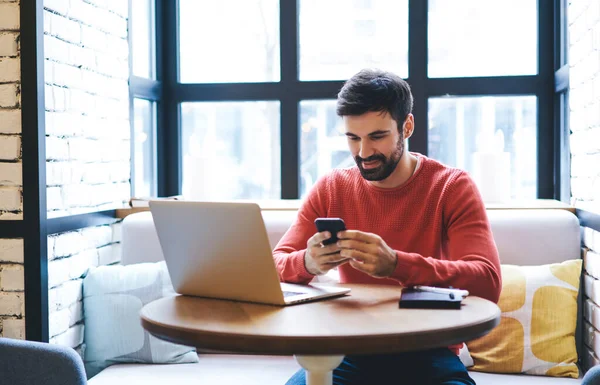 Cheerful Freelancer Beard Browsing Smartphone Smiling While Sitting Table Laptop — Stock Photo, Image