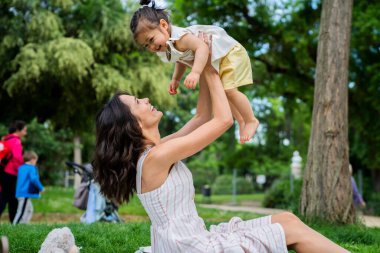 Dikkatli bir annenin battaniyeye oturmuş, sevimli bir çocuk büyütürken Green Park 'ta piknikte kahkahalarla gülmesi. 