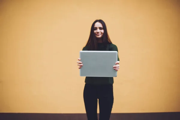 Positive Young Lady Demonstrating Computer Hands While Standing Brown Wall — Stockfoto
