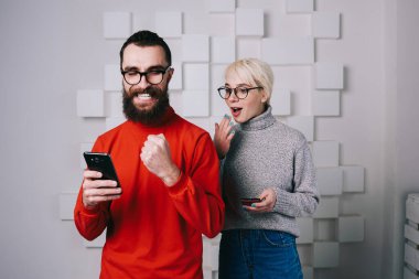 Mutlu genç sakallı adam cep telefonundan iyi haberler okuyor. Zafer işareti yapıyor. Ve sarışın kadın erkeğin omzunun üstünden dikizliyor.